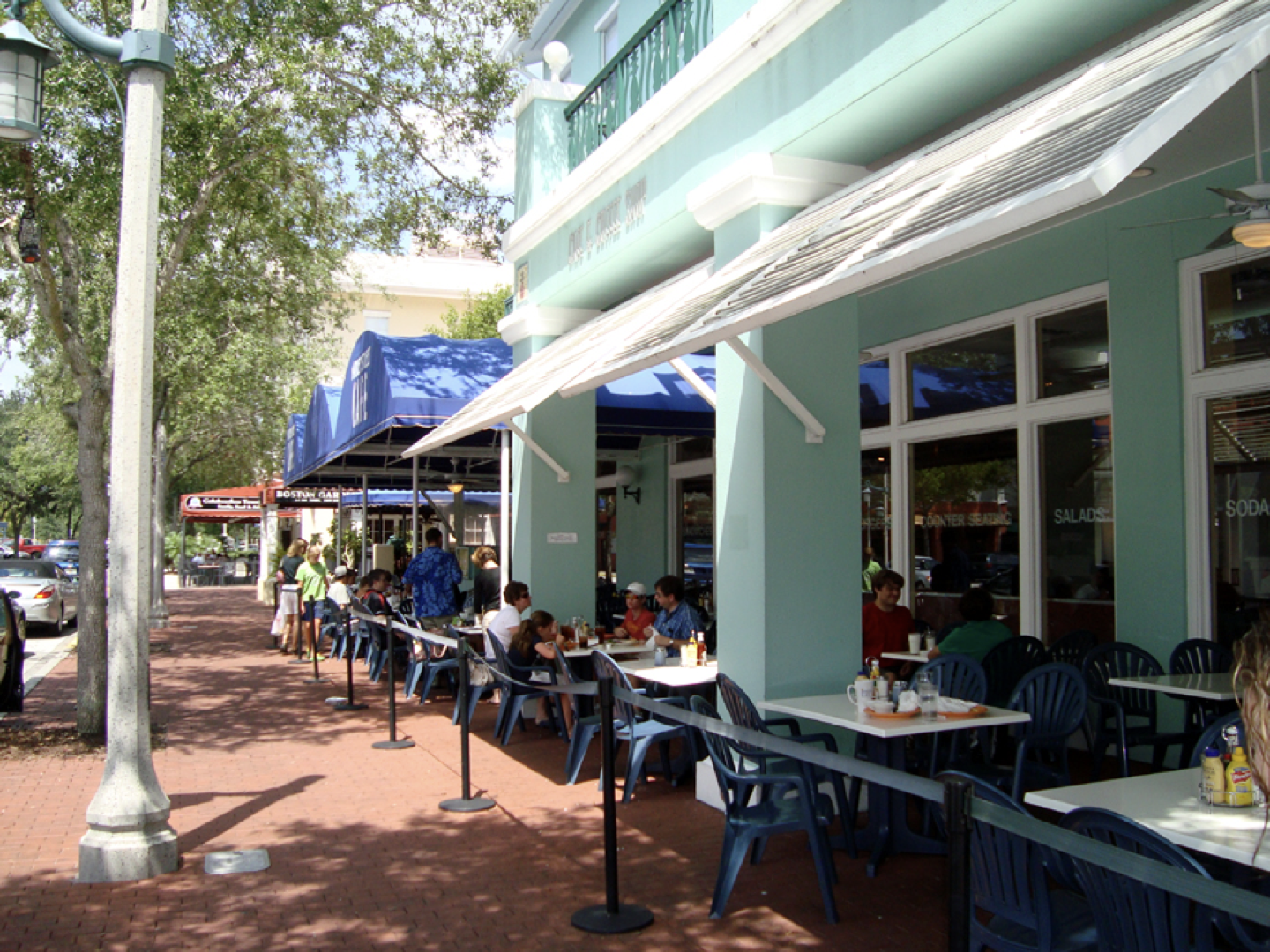a group of people are sitting at tables outside of a restaurant .