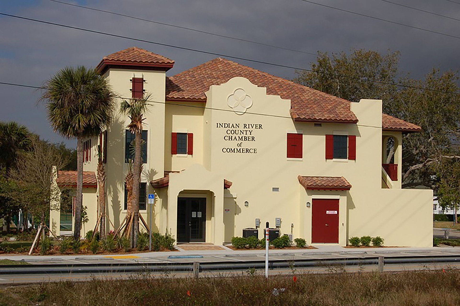 a large yellow building with a red door and shutters