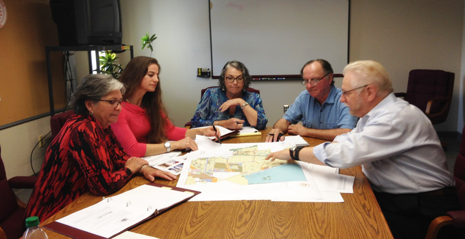 a group of people are sitting around a table looking at a map .
