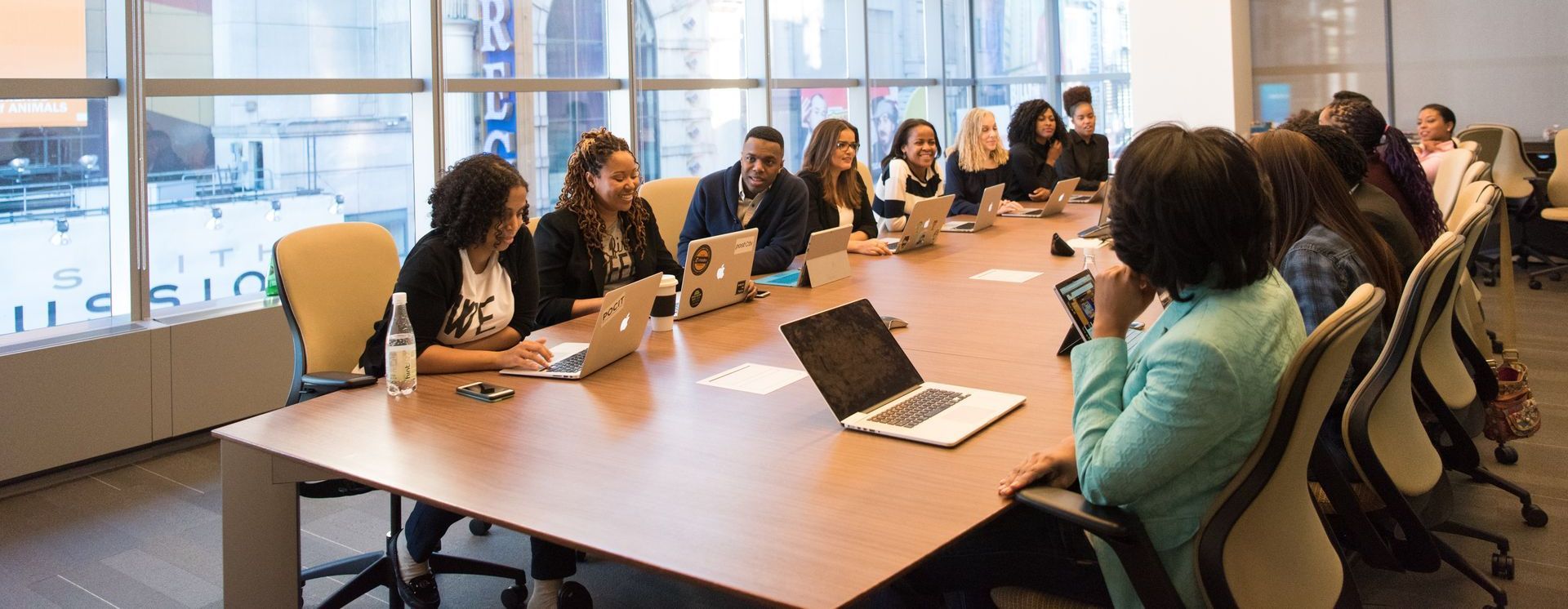 Meeting room with large group of people gathered around a conference table.