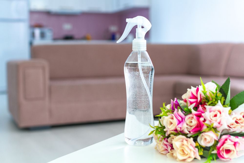 A spray bottle is sitting on a table next to a bouquet of flowers.