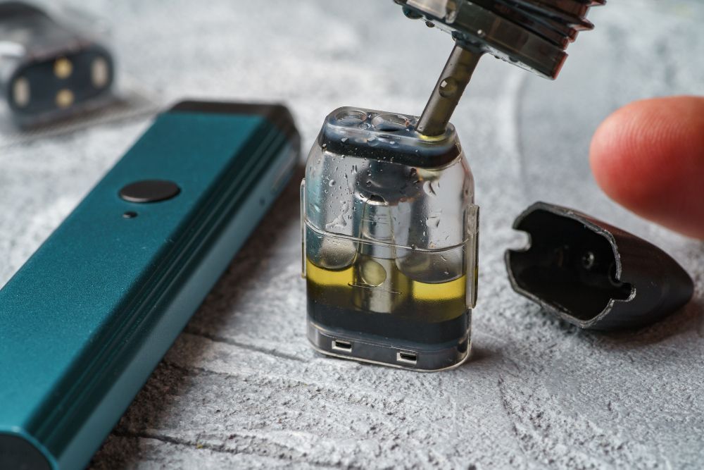 A person is filling a vape pen with liquid.