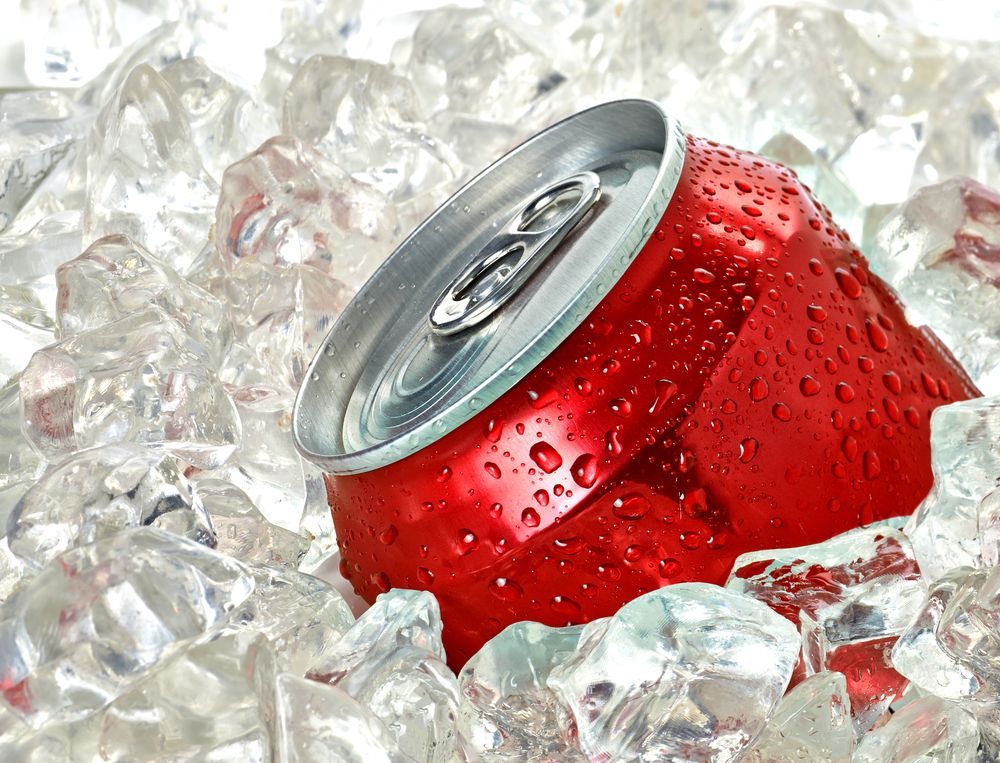 A red soda can is sitting on top of ice cubes.