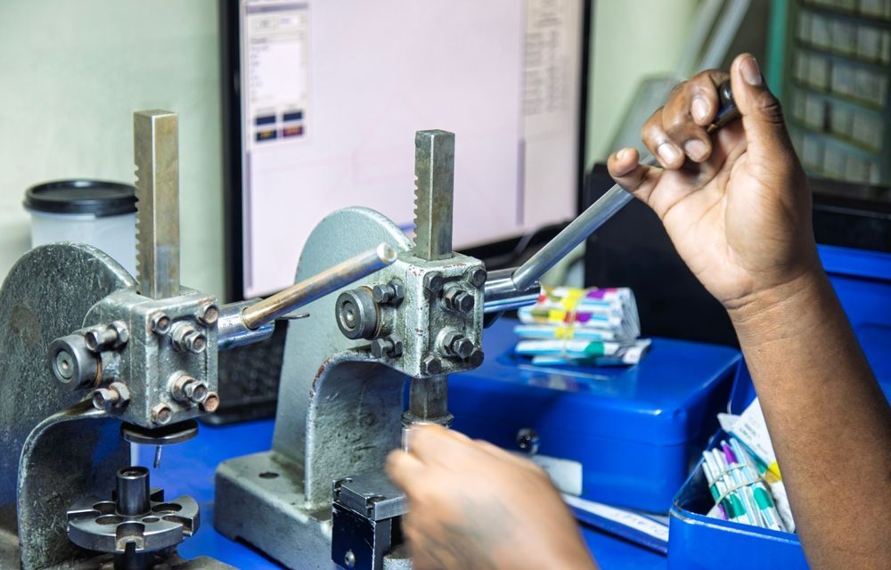 A person is working on a machine in front of a computer.
