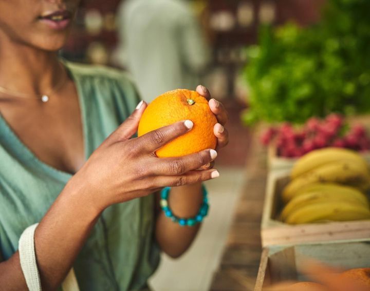 A woman is holding an orange in her hands.