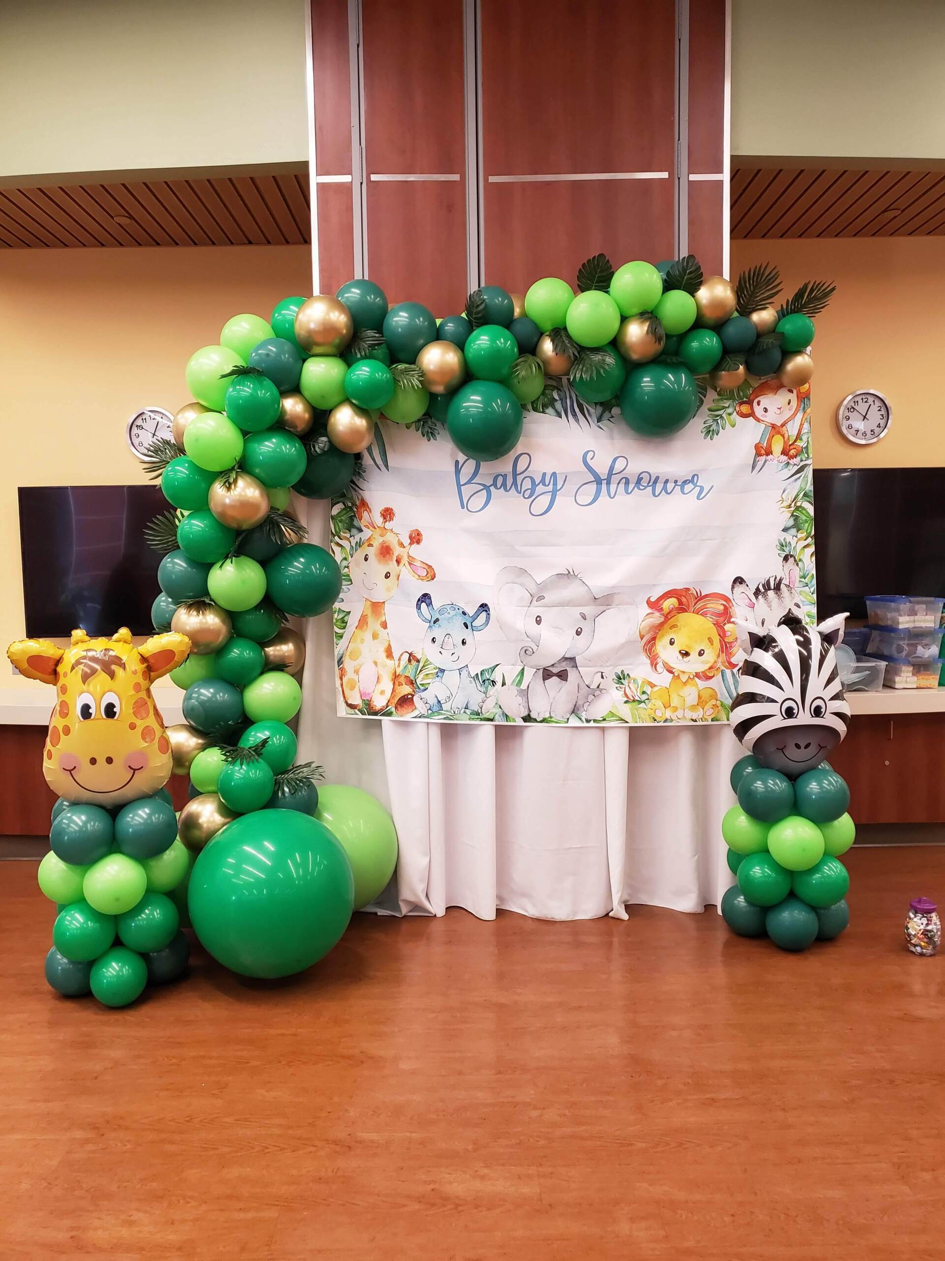 A room decorated with green and gold balloons for a baby shower.