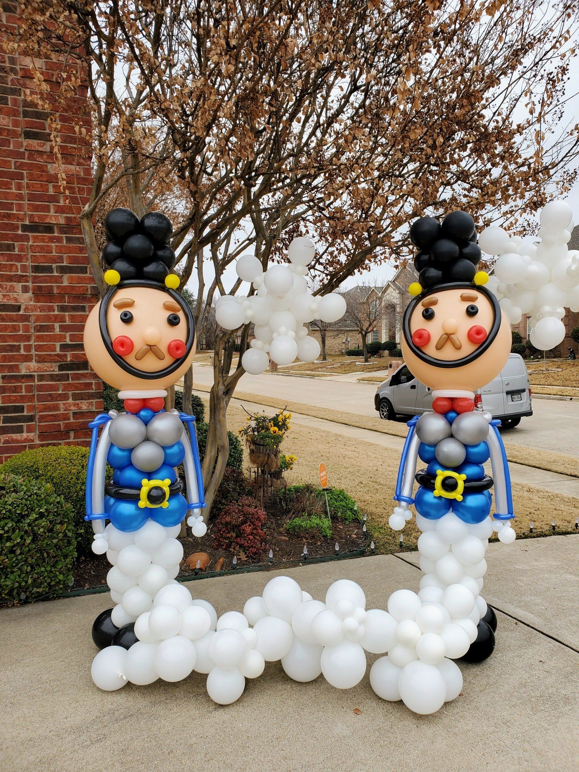 Two nutcrackers made out of balloons are standing next to each other on a sidewalk.