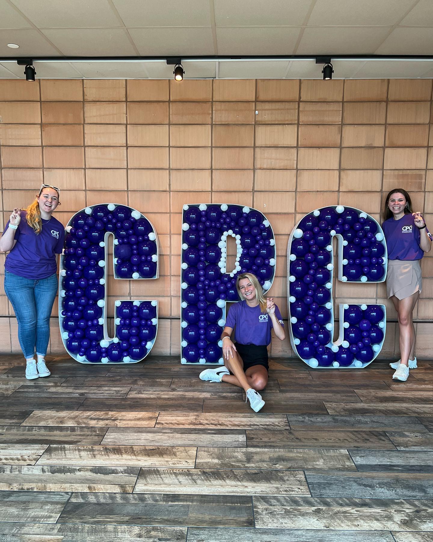 Three women are posing for a picture in front of a large sign that says crc.