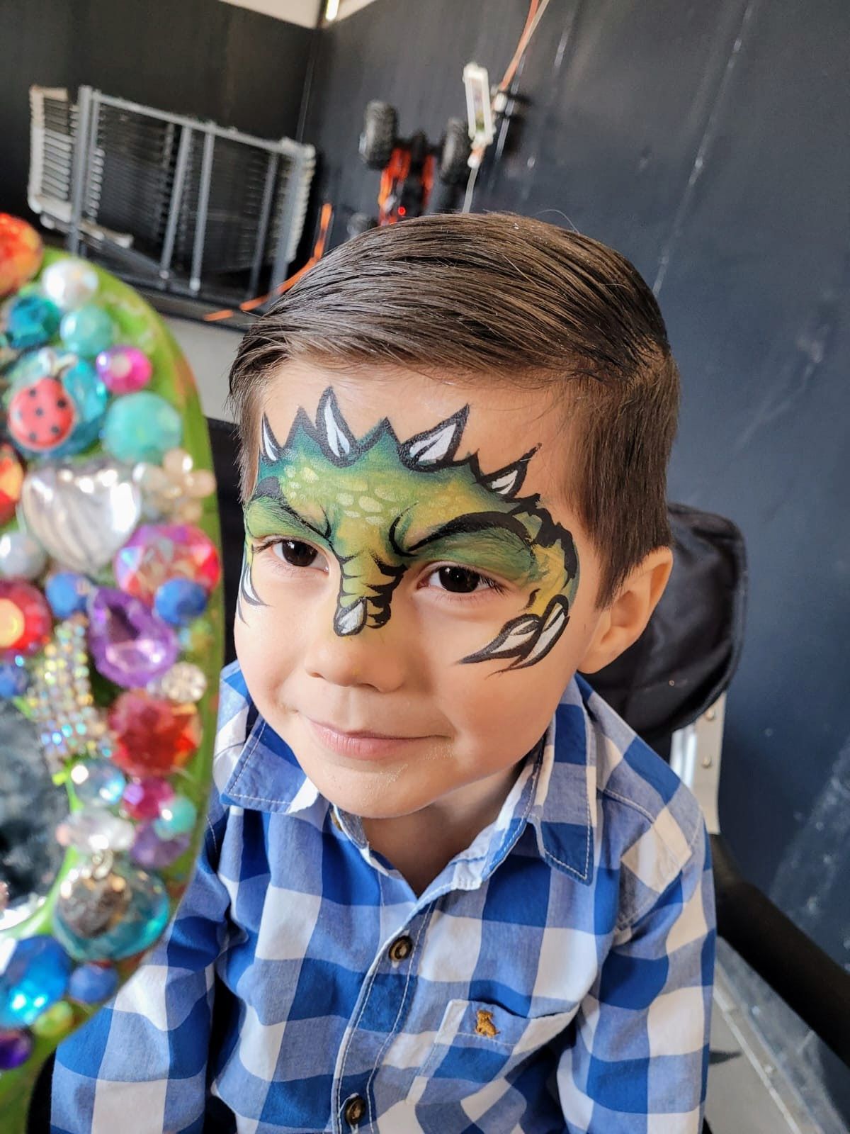 A young boy with a dinosaur painted on his face.