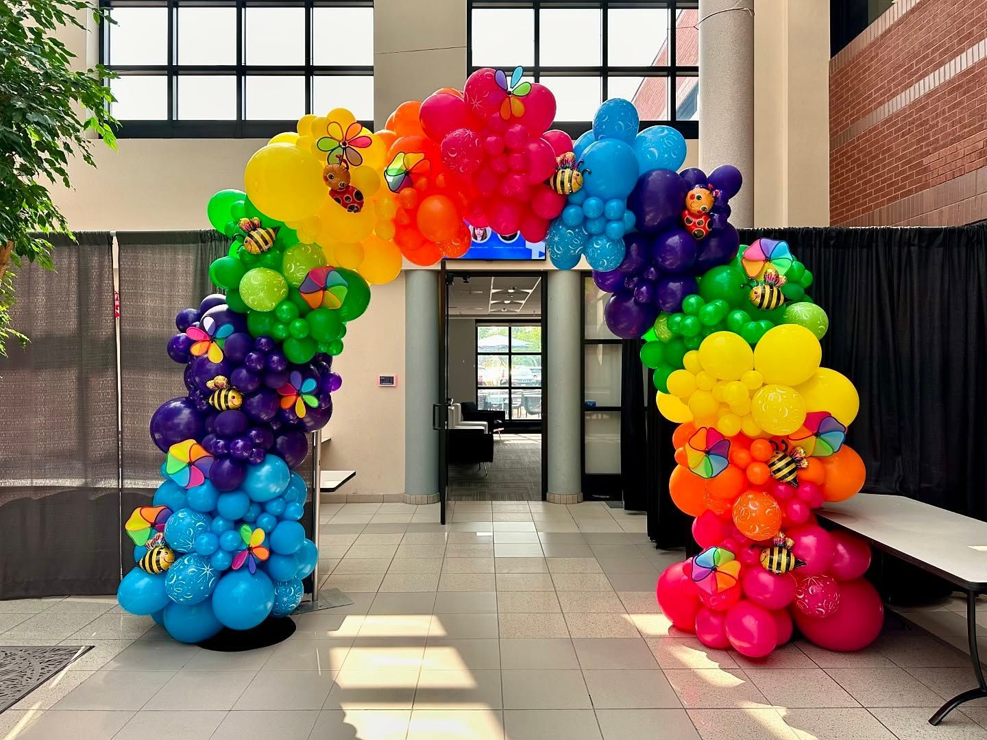 Colorful balloon arch installation for a school commencement event with bright rainbow balloons framing an entrance.