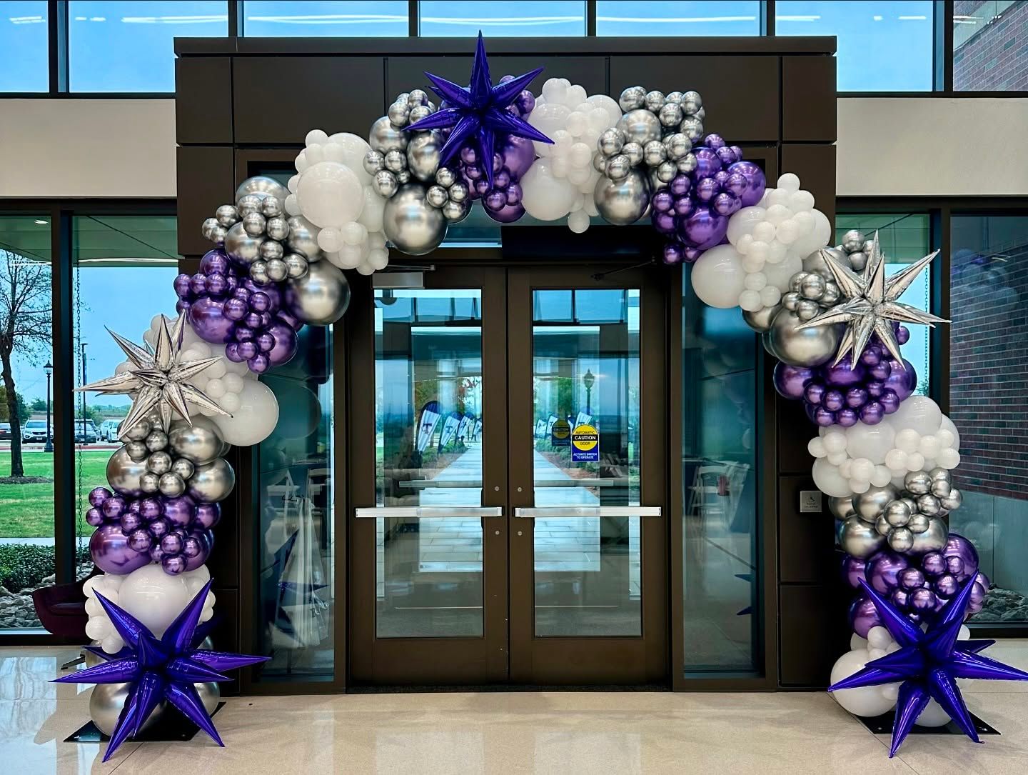 Organic balloon arch installation with mixed balloon sizes for corporate event entrance