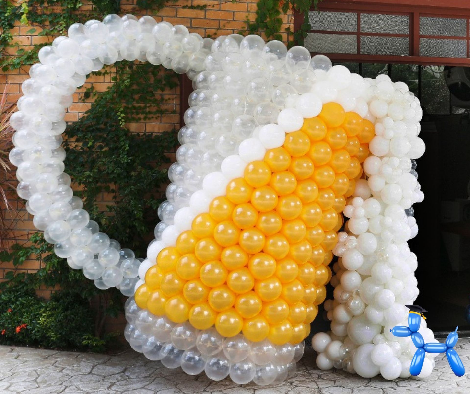Large balloon sculpture of a beer much with golden rod, white and clear balloons tilted to look like its pouring beer