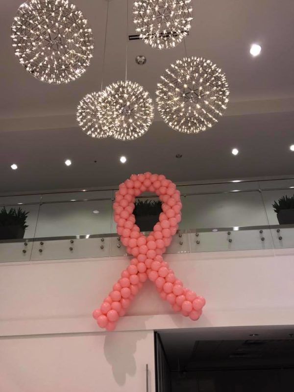 A pink ribbon made out of balloons is hanging from the ceiling
