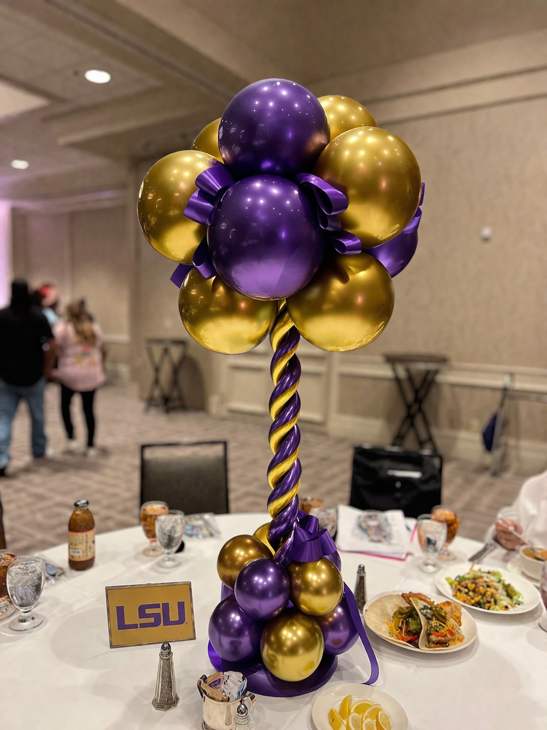 a unique style balloon centerpiece customized in school colors purple and gold for LSU.
