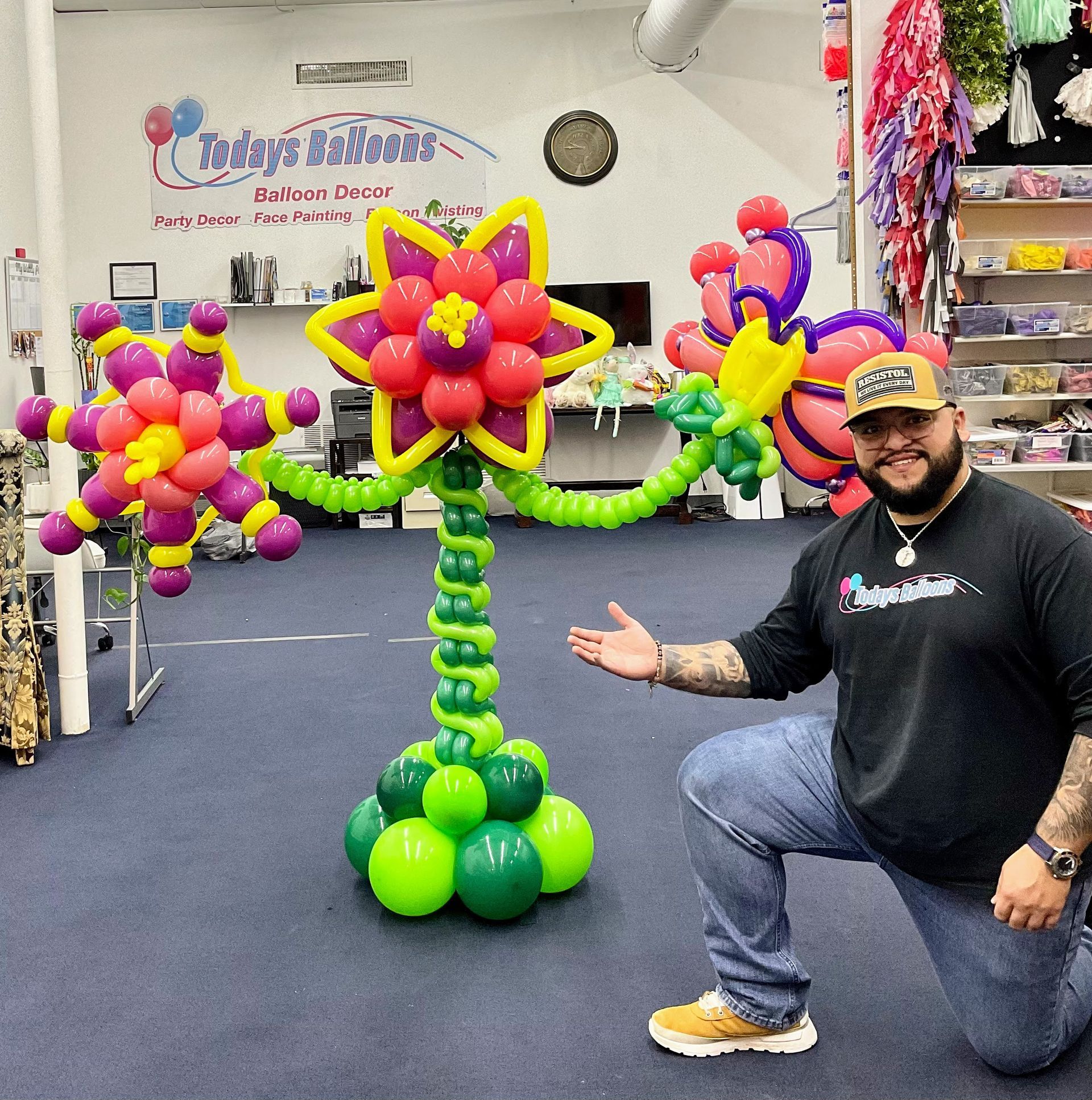 A man kneeling in front of a flower made of balloons