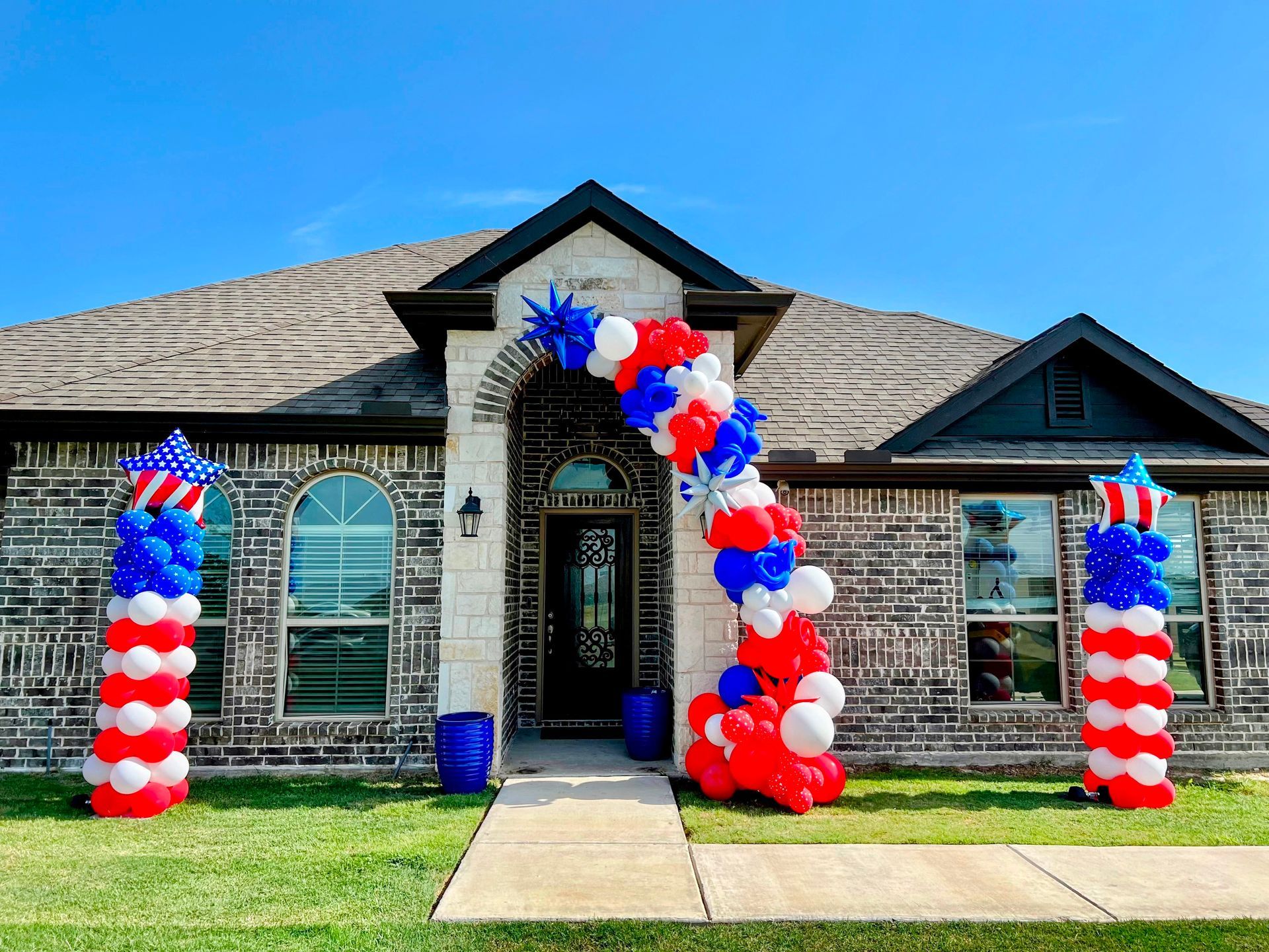 A house is decorated with red , white and blue balloons.