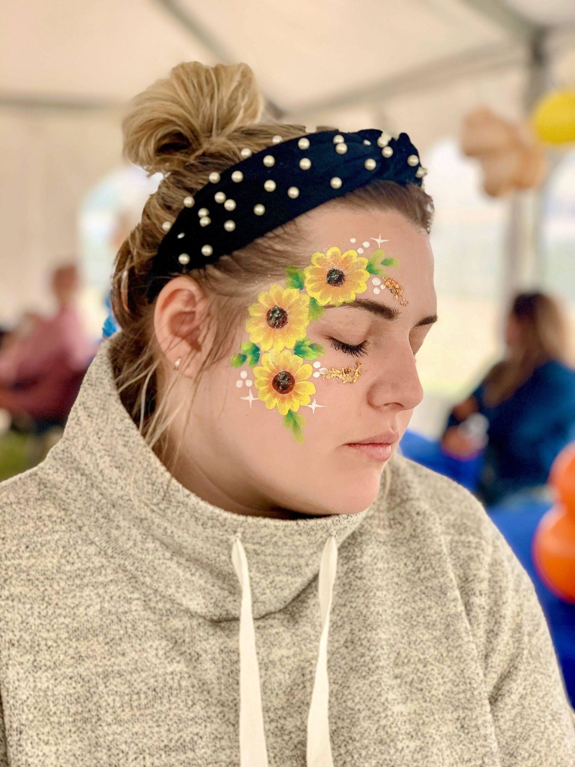 A woman with sunflowers painted on her face.