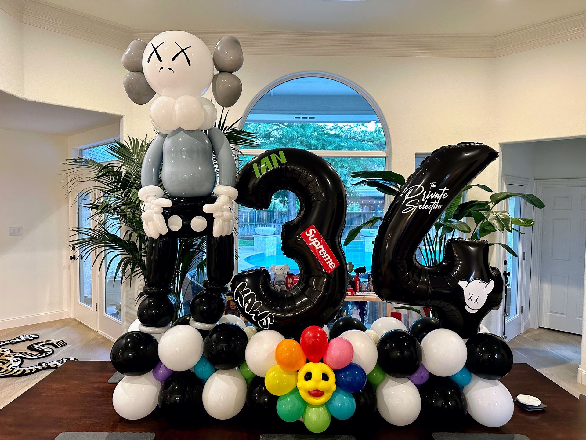 A room filled with balloons and a statue of kaws.