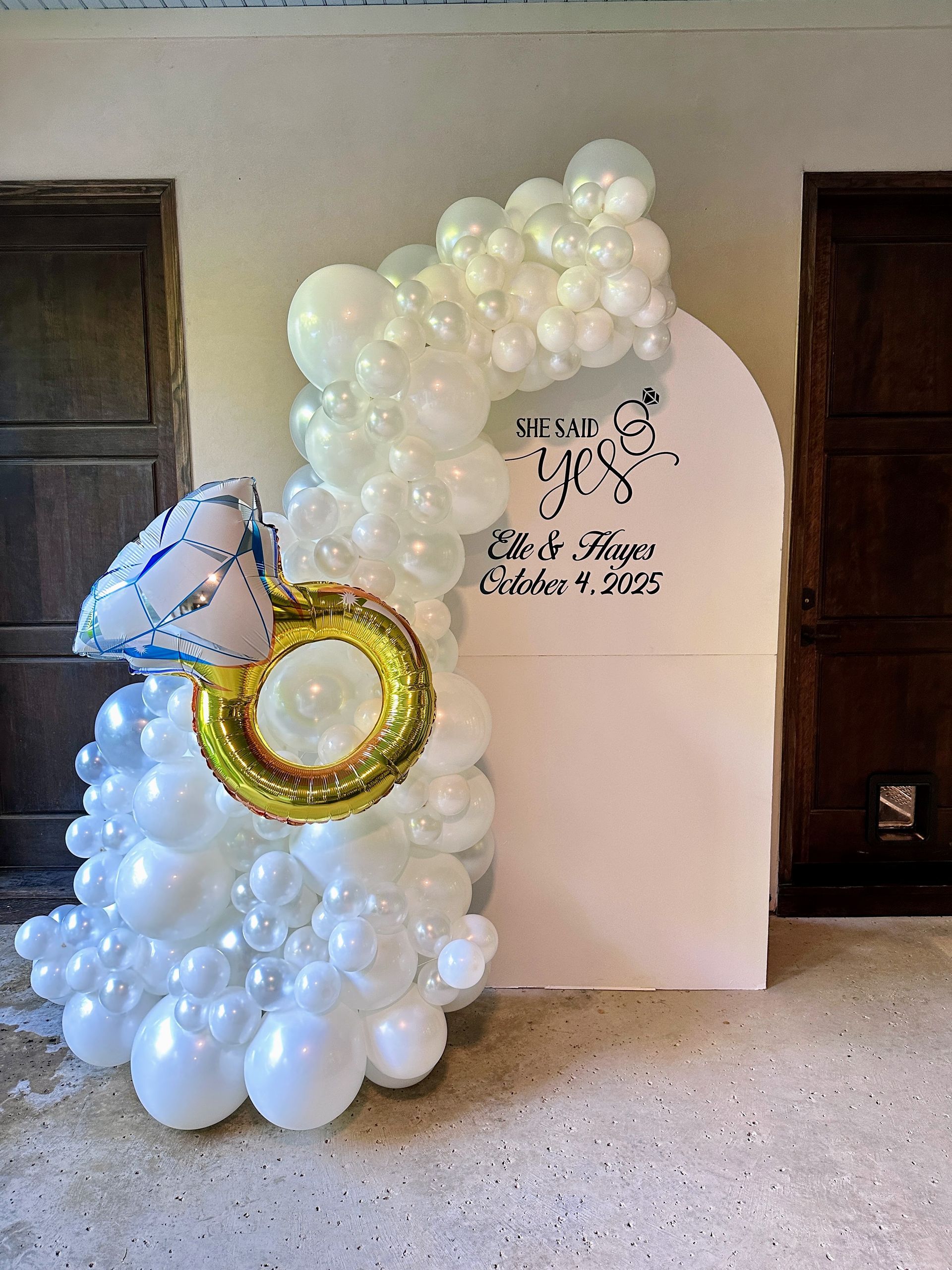 Engagement themed balloon garland featuring white and neutral balloons with a ring accent and custom backdrop