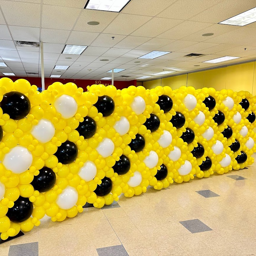 A wall made out of yellow and black balloons