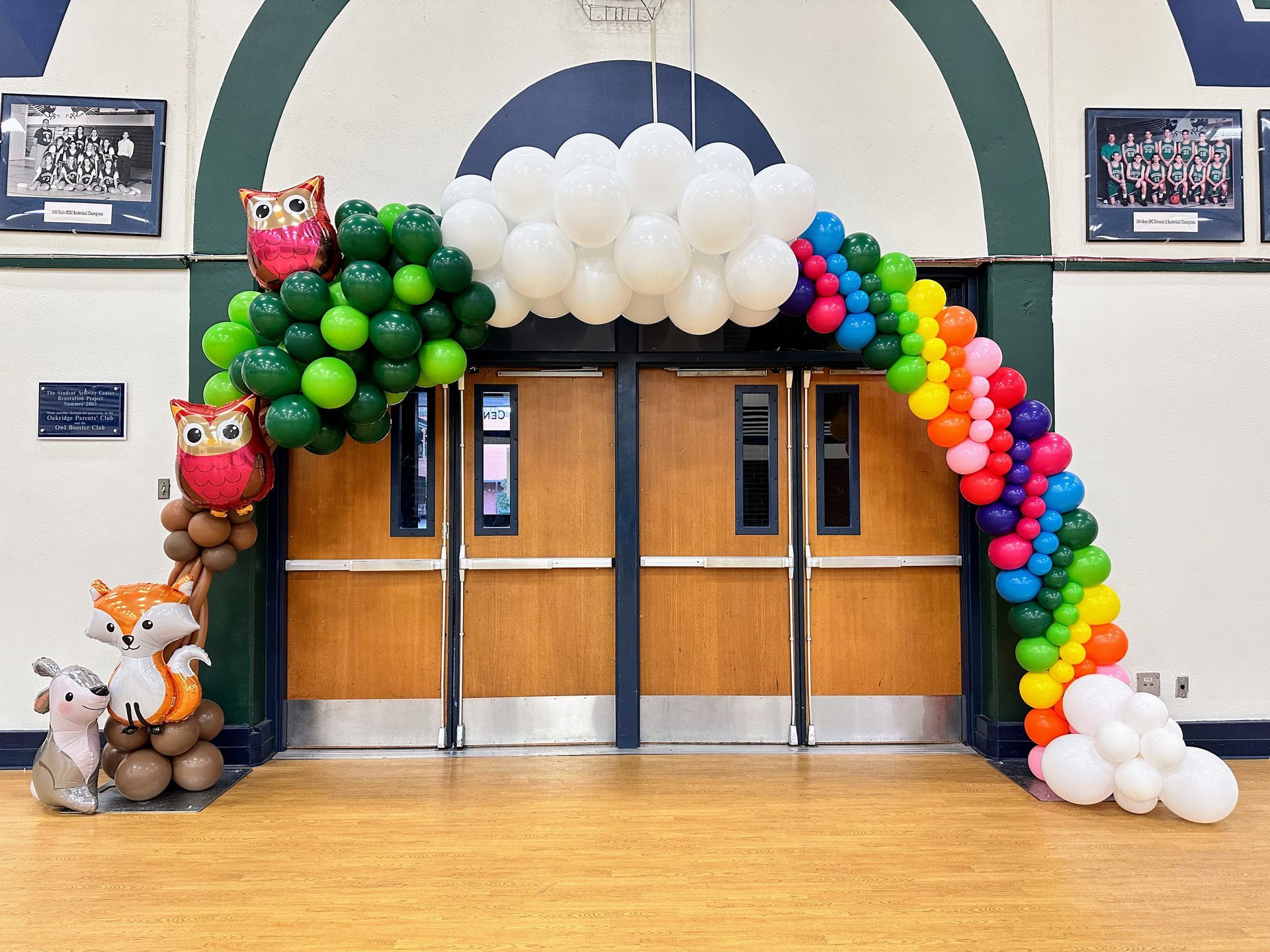 Back to school balloon arch installed at school entrance with rainbow balloon décor and themed accents for welcoming students