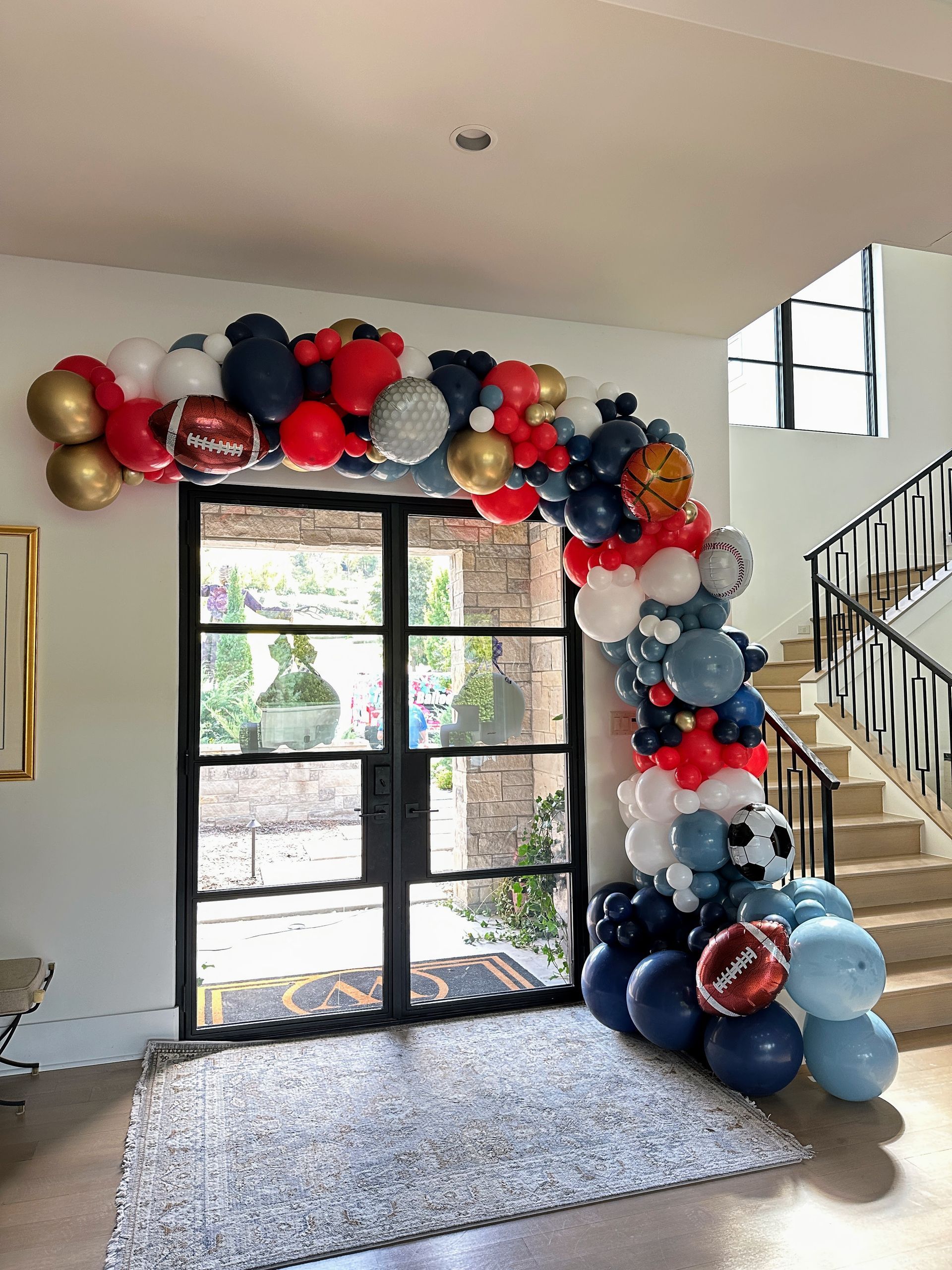 Sports themed balloon garland featuring red, black, silver, and football accents for a sports event