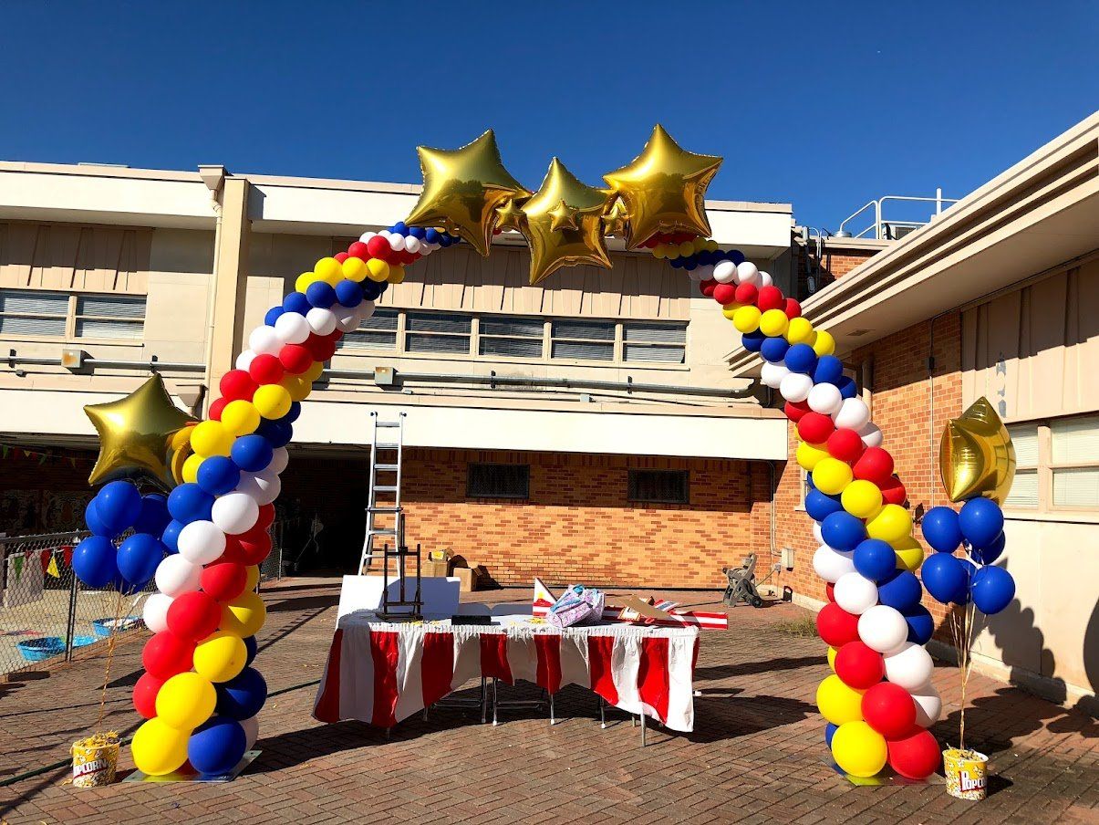 A bunch of balloons are sitting in front of a building.