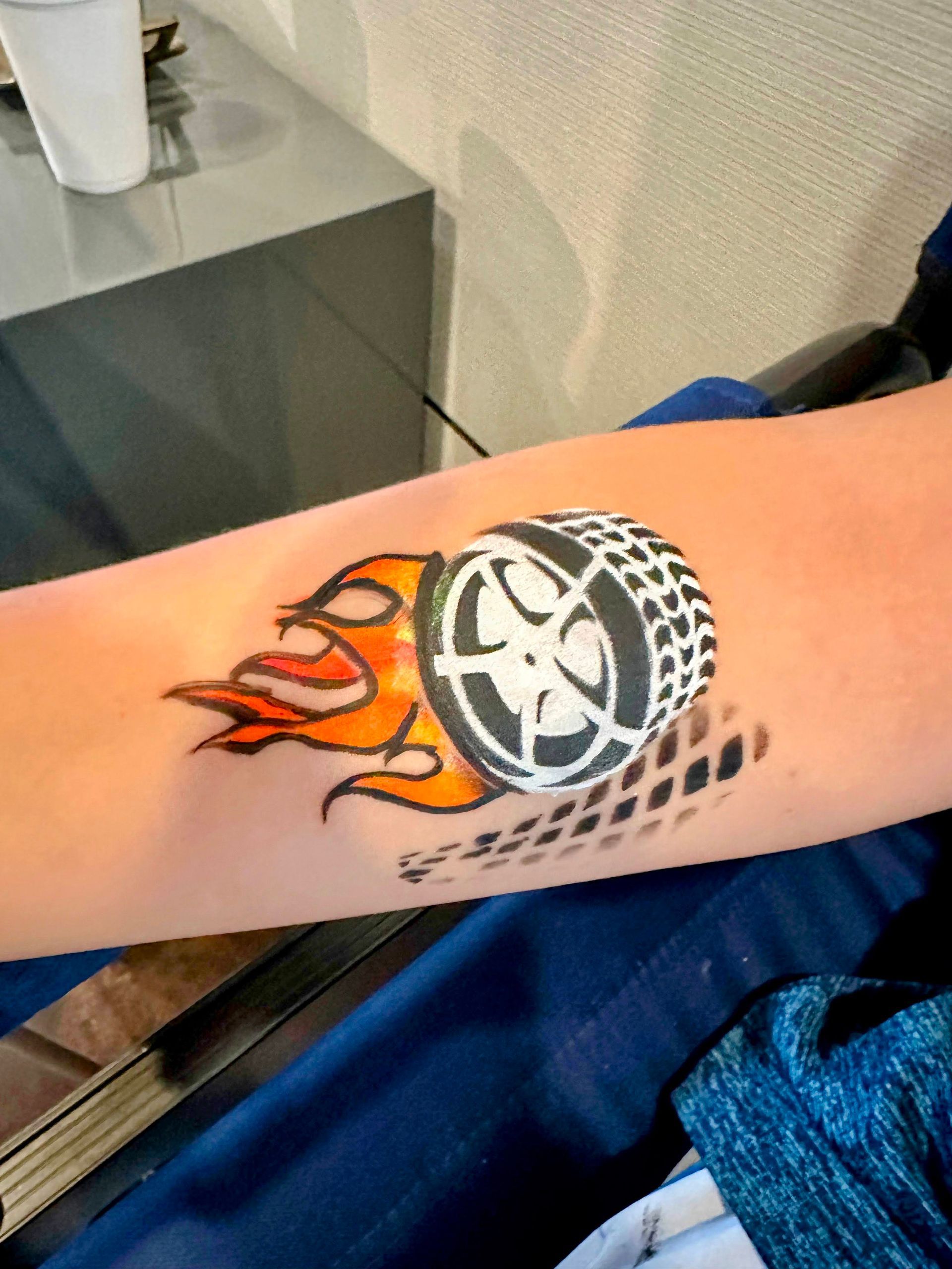 A person has a wheel with flames painted on their arm