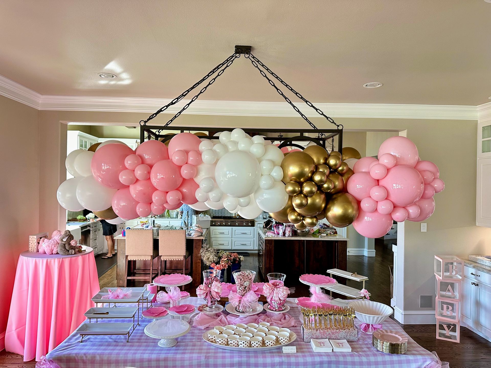 Pastel colored balloon garland over a backdrop panel with 