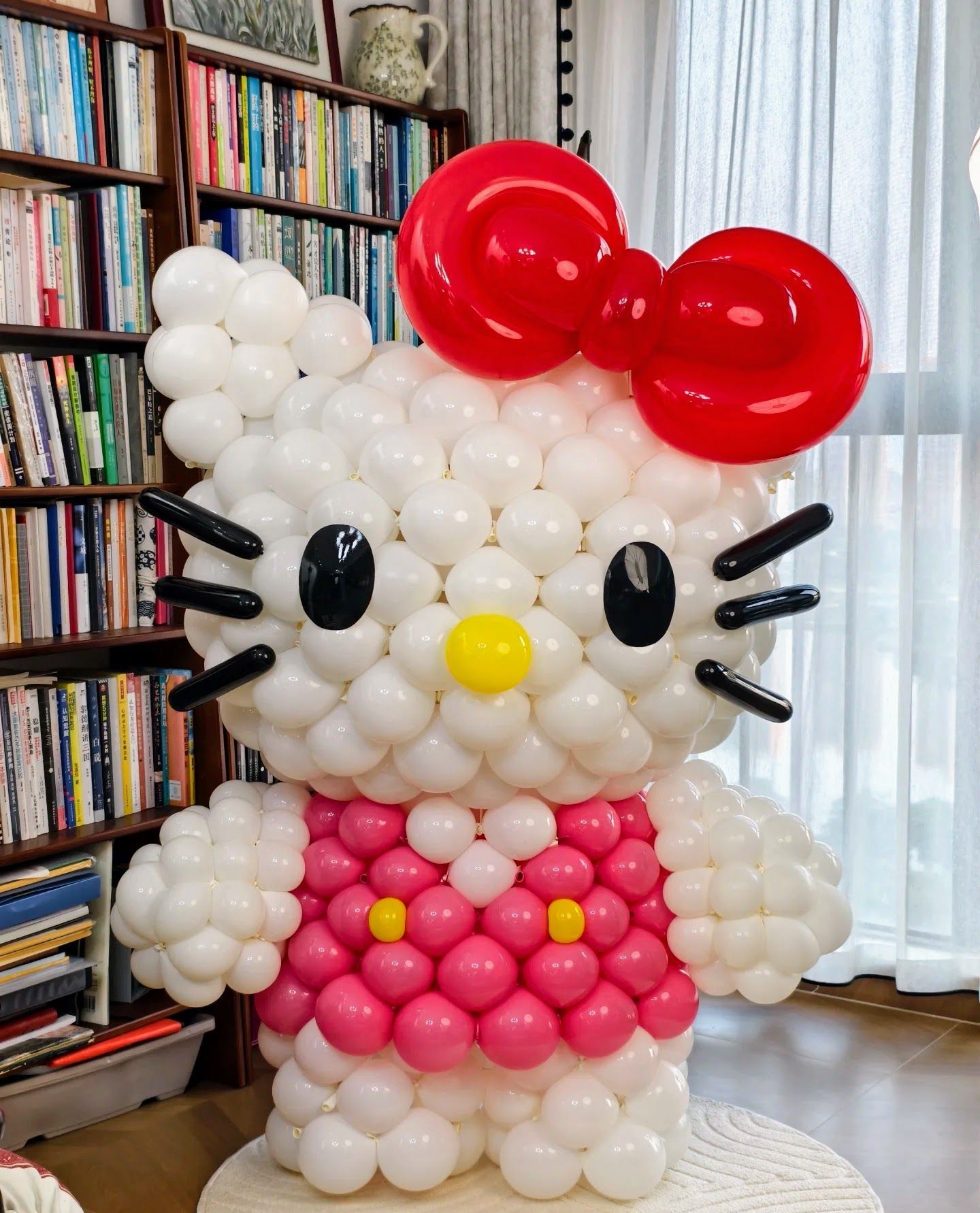 Hello Kitty balloon sculpture: white, pink, red, black latex with bow and yellow nose.