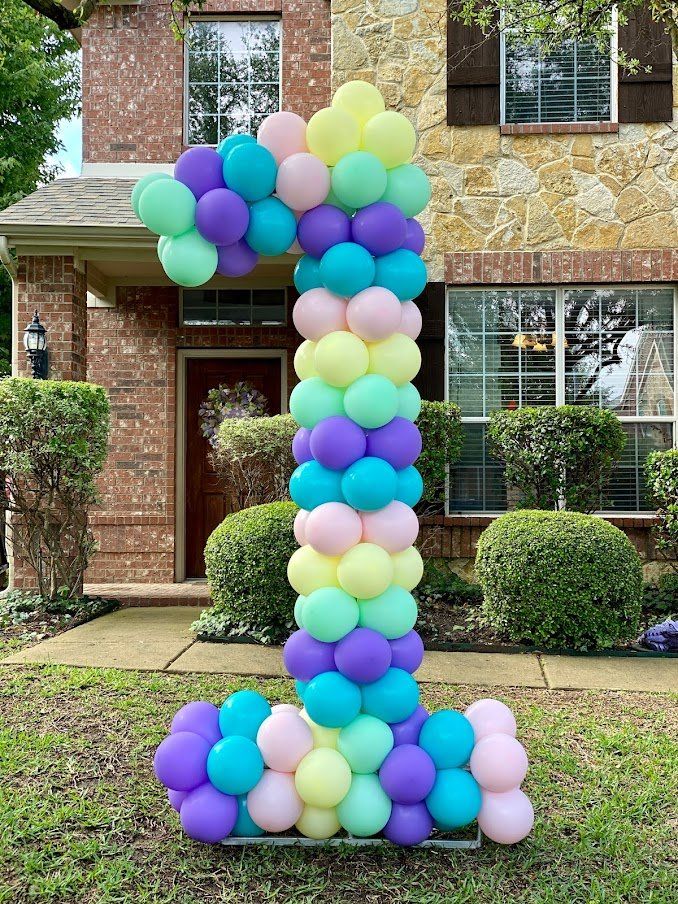 A large number 1 made of balloons in front of a house.