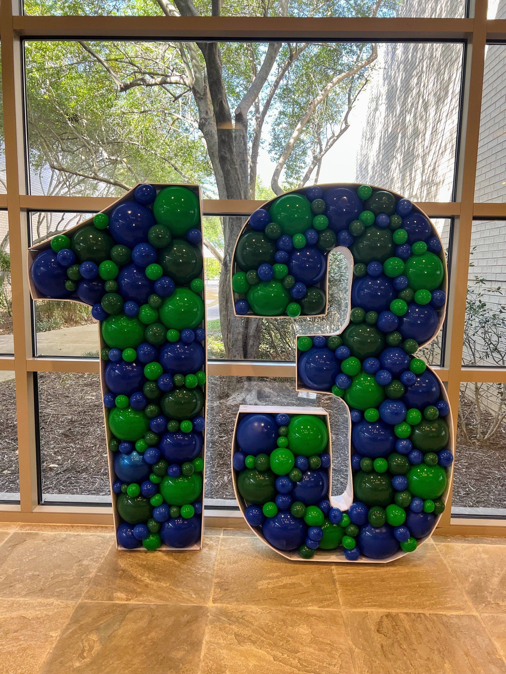 The number 13 is made of blue and green balloons.