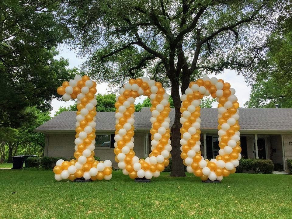 The number 100 is made out of balloons in front of a house.