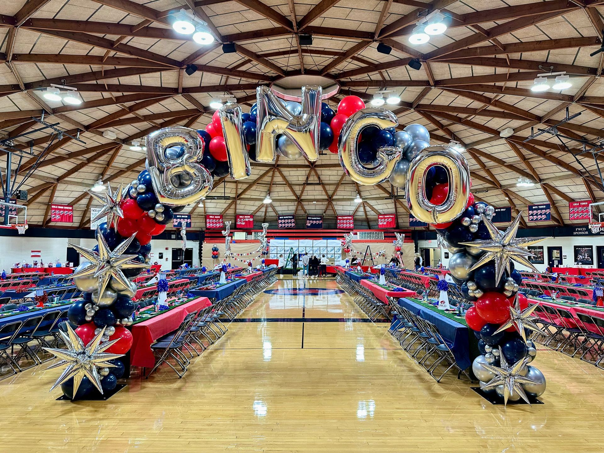 Large scale balloon installation for corporate or school event inside a gymnasium with hanging balloon decor