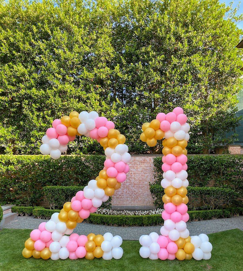 The number 21 is made of pink , white and gold balloons