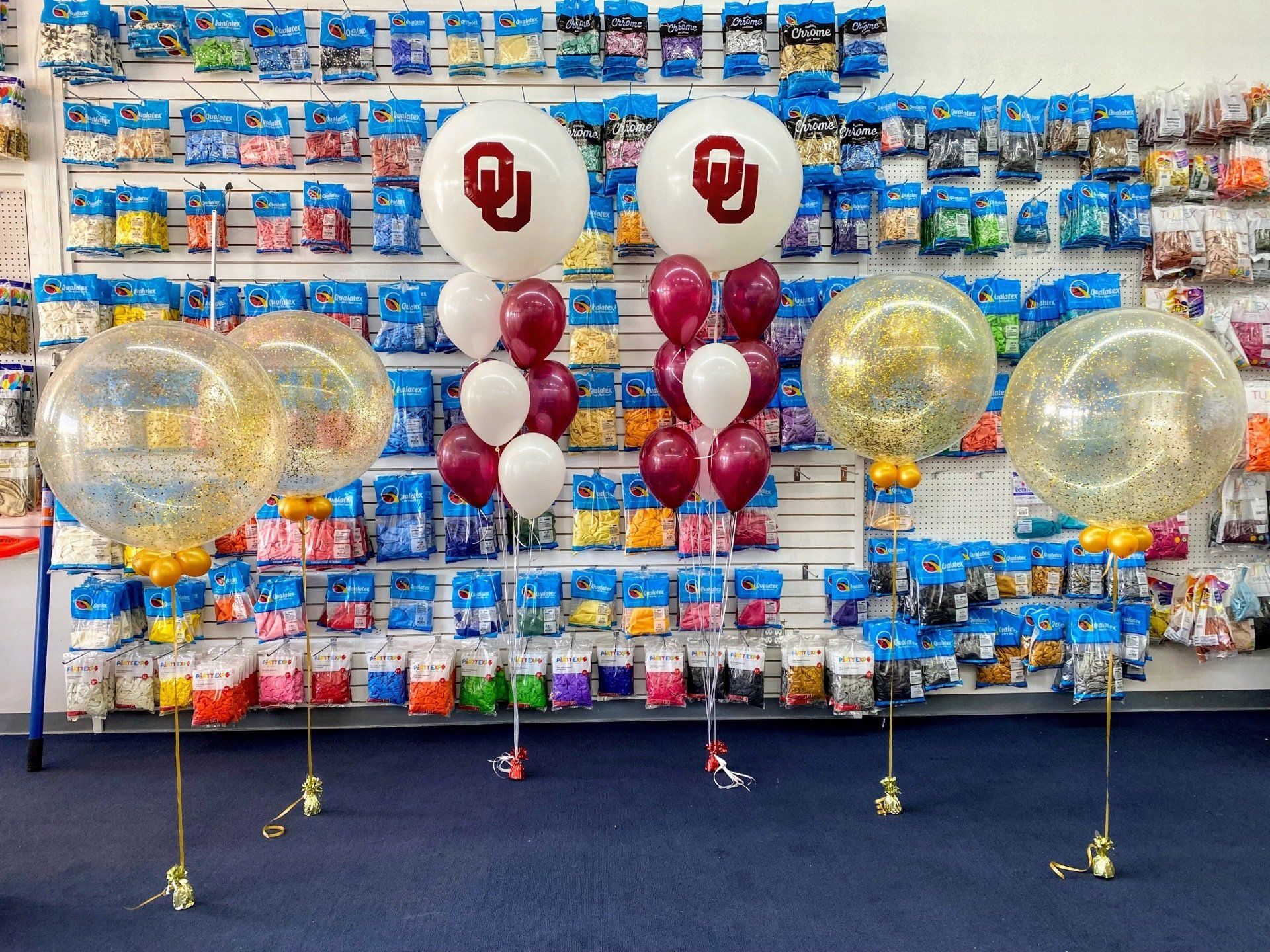 A bunch of balloons are sitting in front of a wall of balloons.