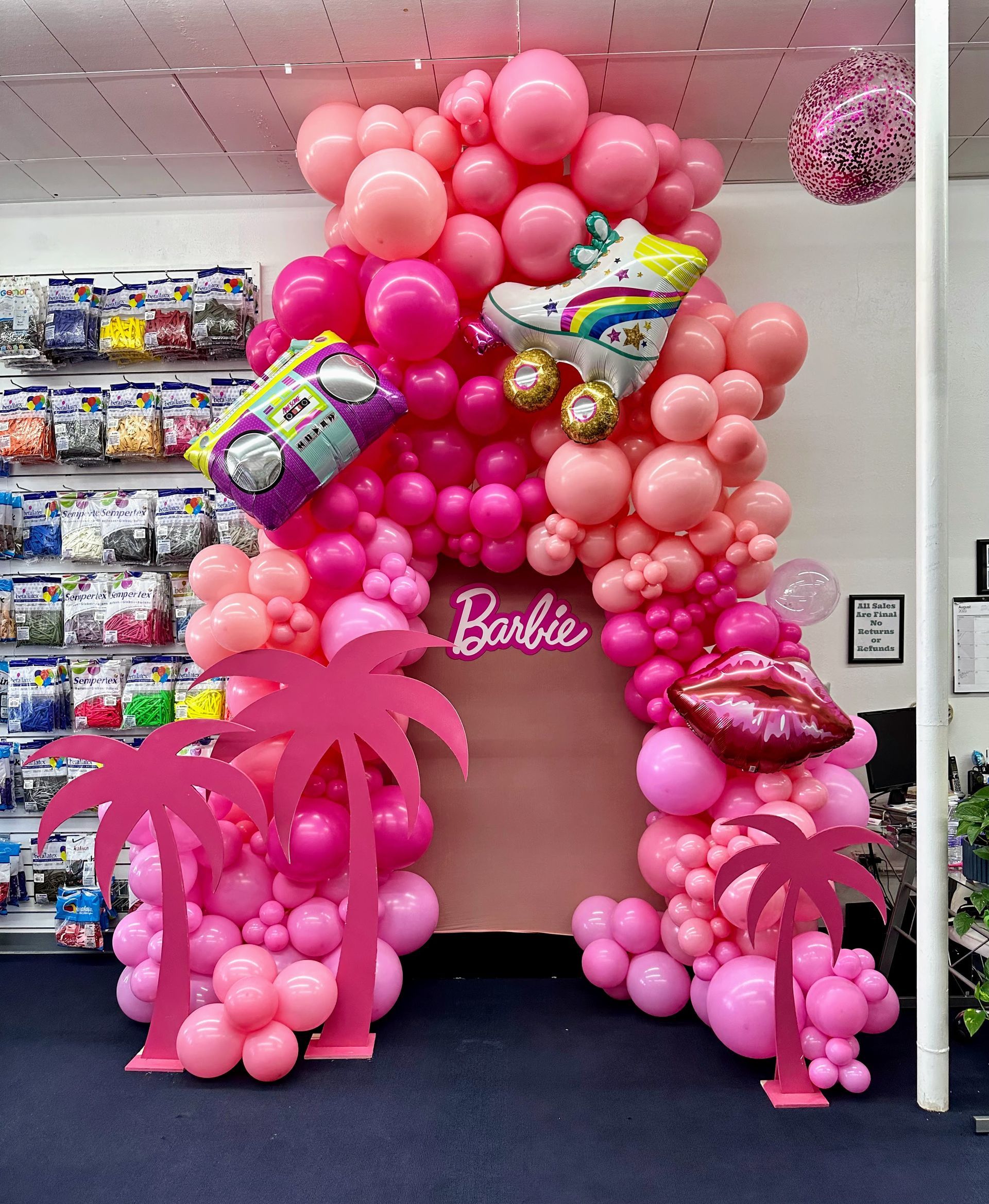 A bunch of pink balloons are hanging from the ceiling in a room.