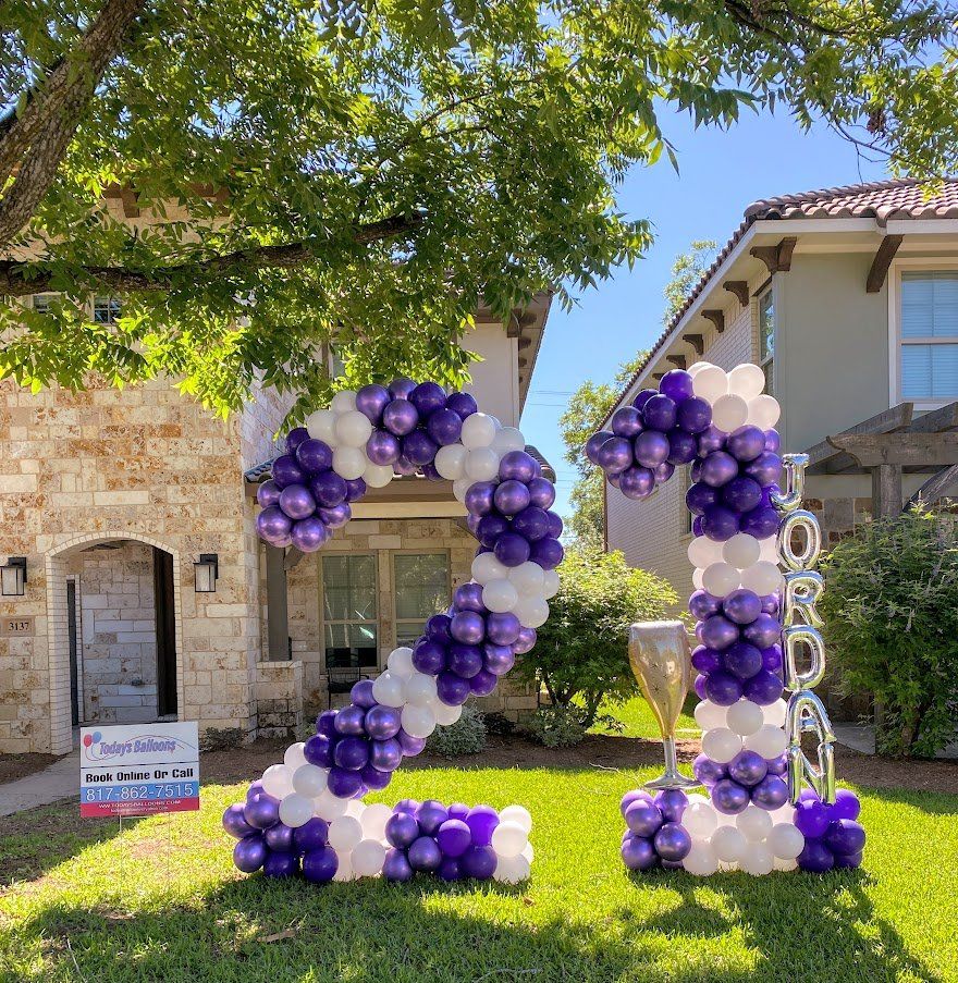 The number 21 is made of purple and white balloons in front of a house.