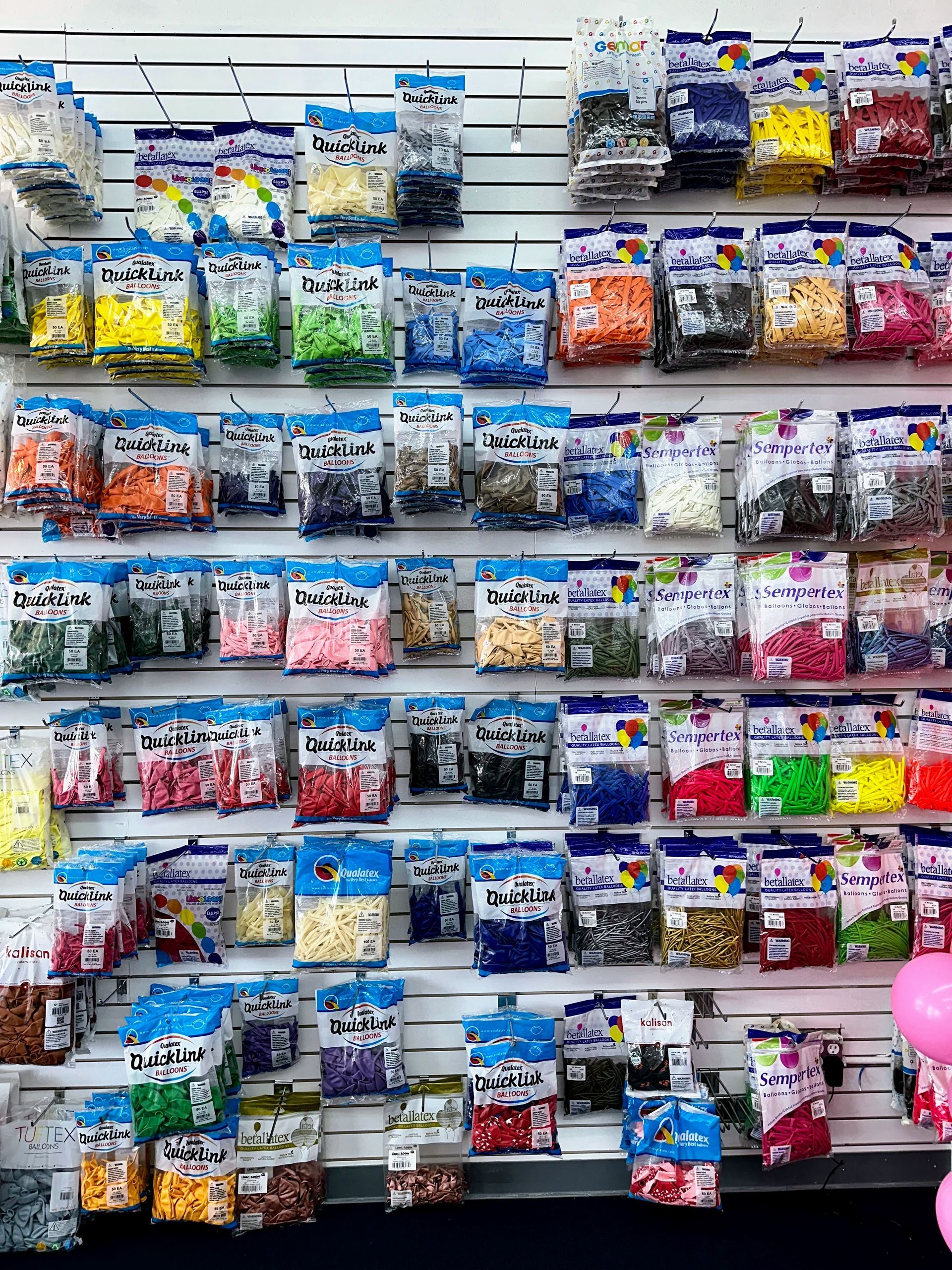 A wall filled with lots of bags of beads and balloons.