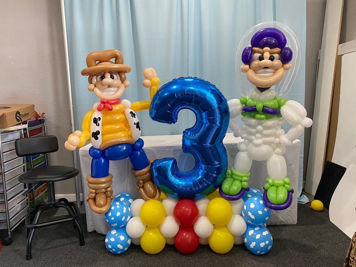 Woody and buzz lightyear made out of balloons are sitting on a table.