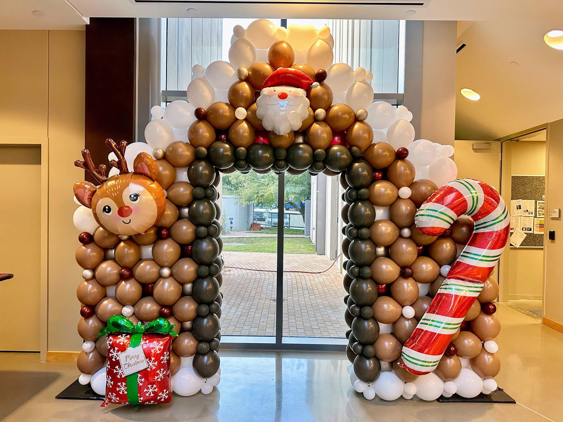 Christmas balloon arch featuring reindeer accents and festive holiday balloons installed at an indoor venue entrance