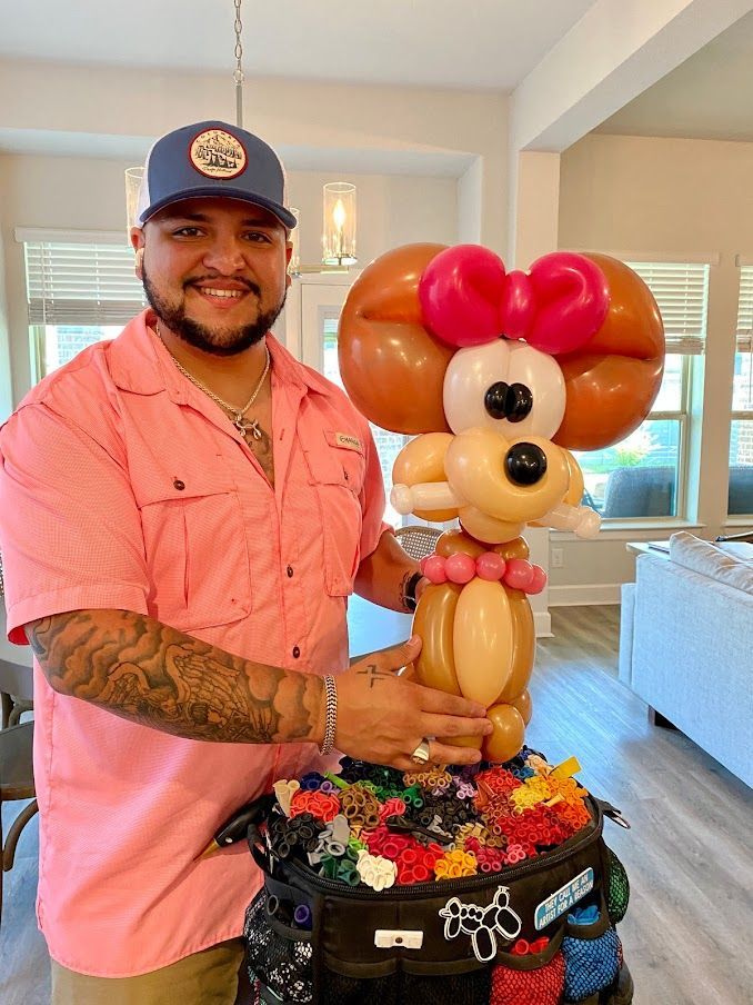A man in a pink shirt is holding a balloon dog.