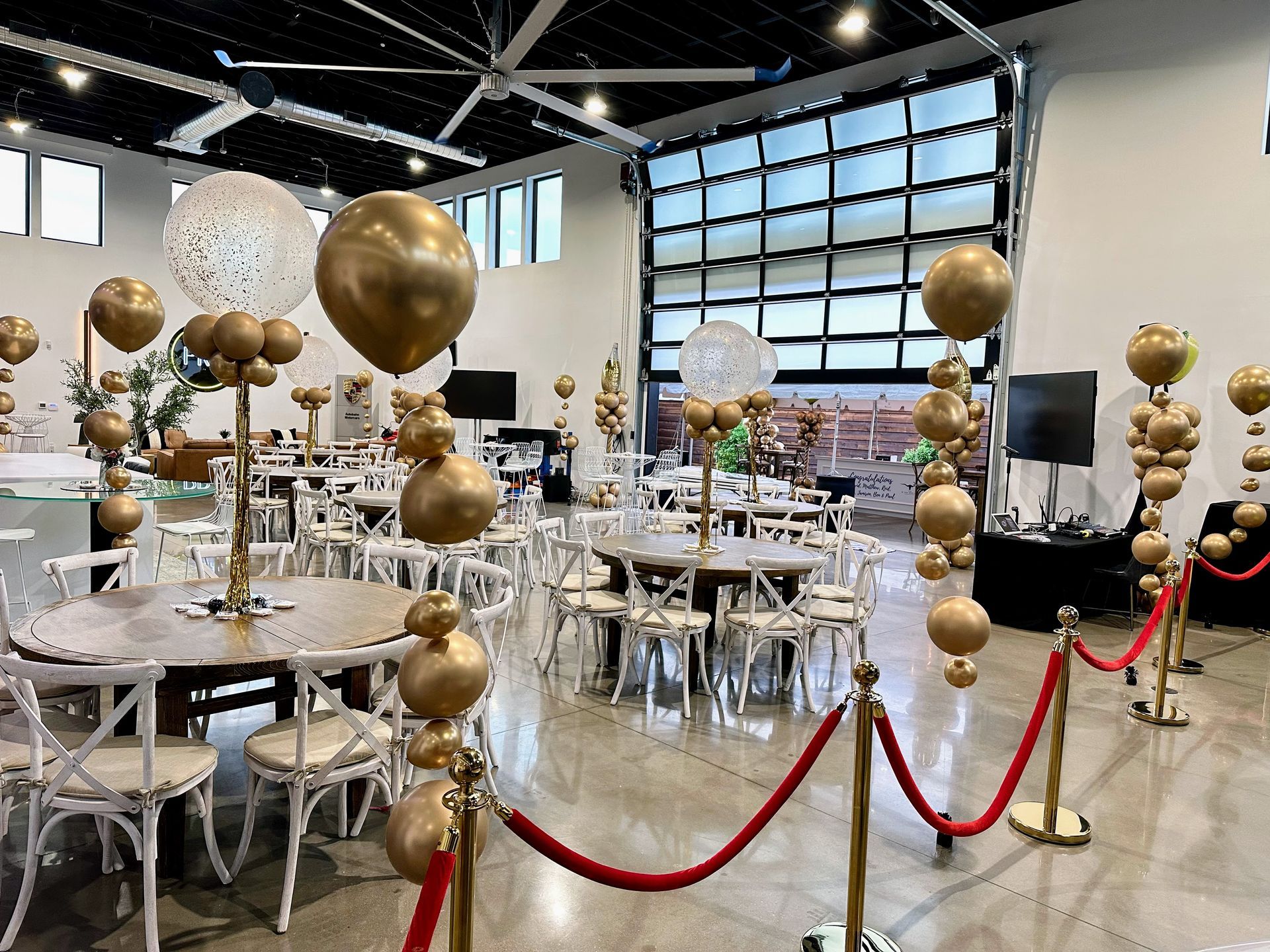Elegant corporate event balloon decor with gold balloon accents and velvet rope stanchions inside a large venue