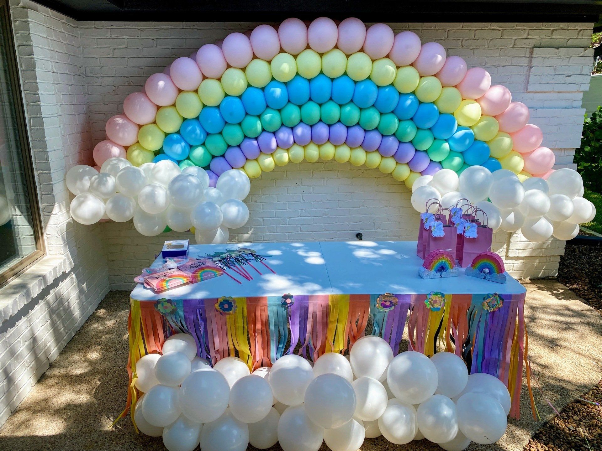 A table decorated with balloons and a rainbow in the background.