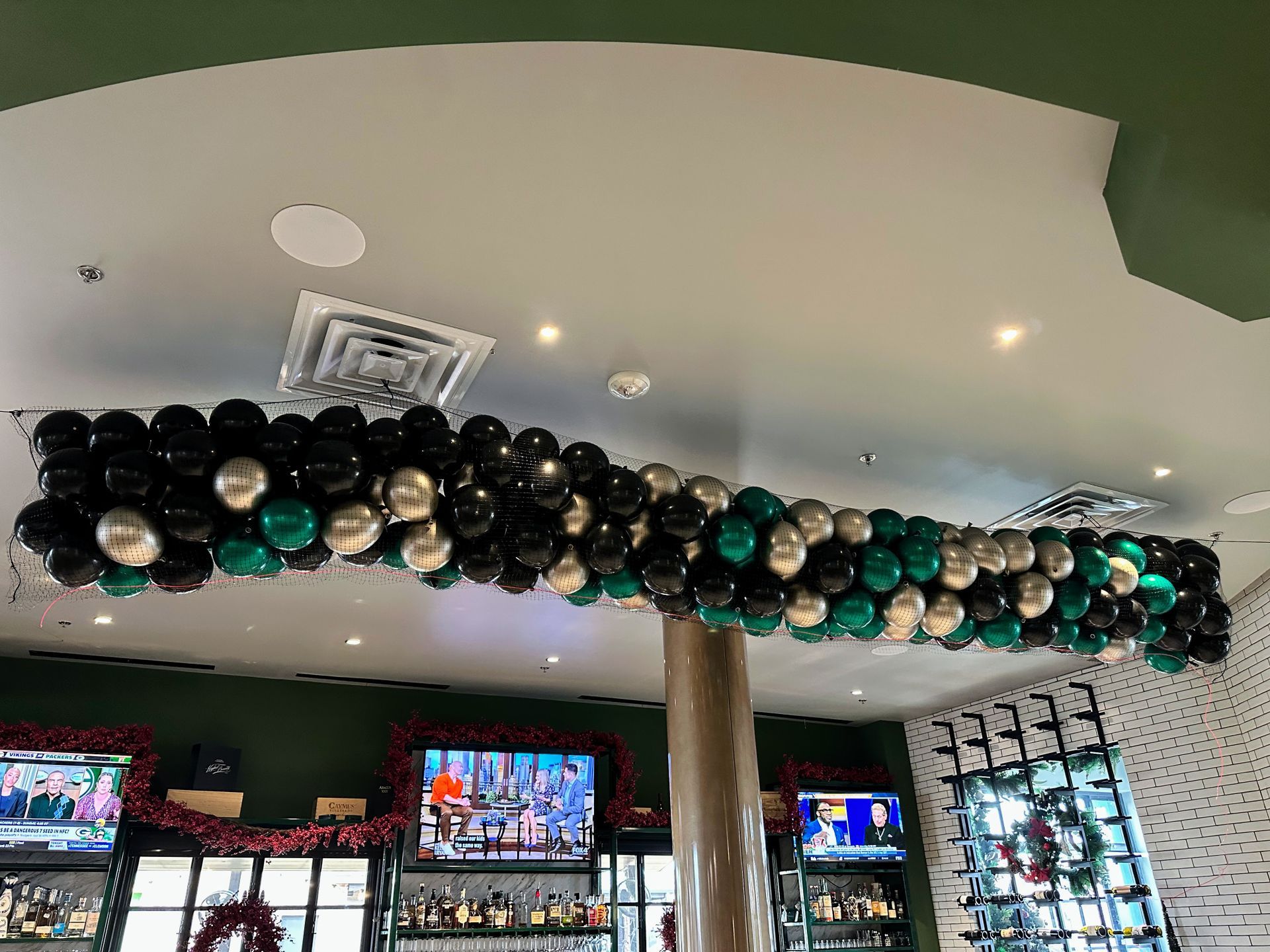 A bunch of balloons are hanging from the ceiling of a restaurant.