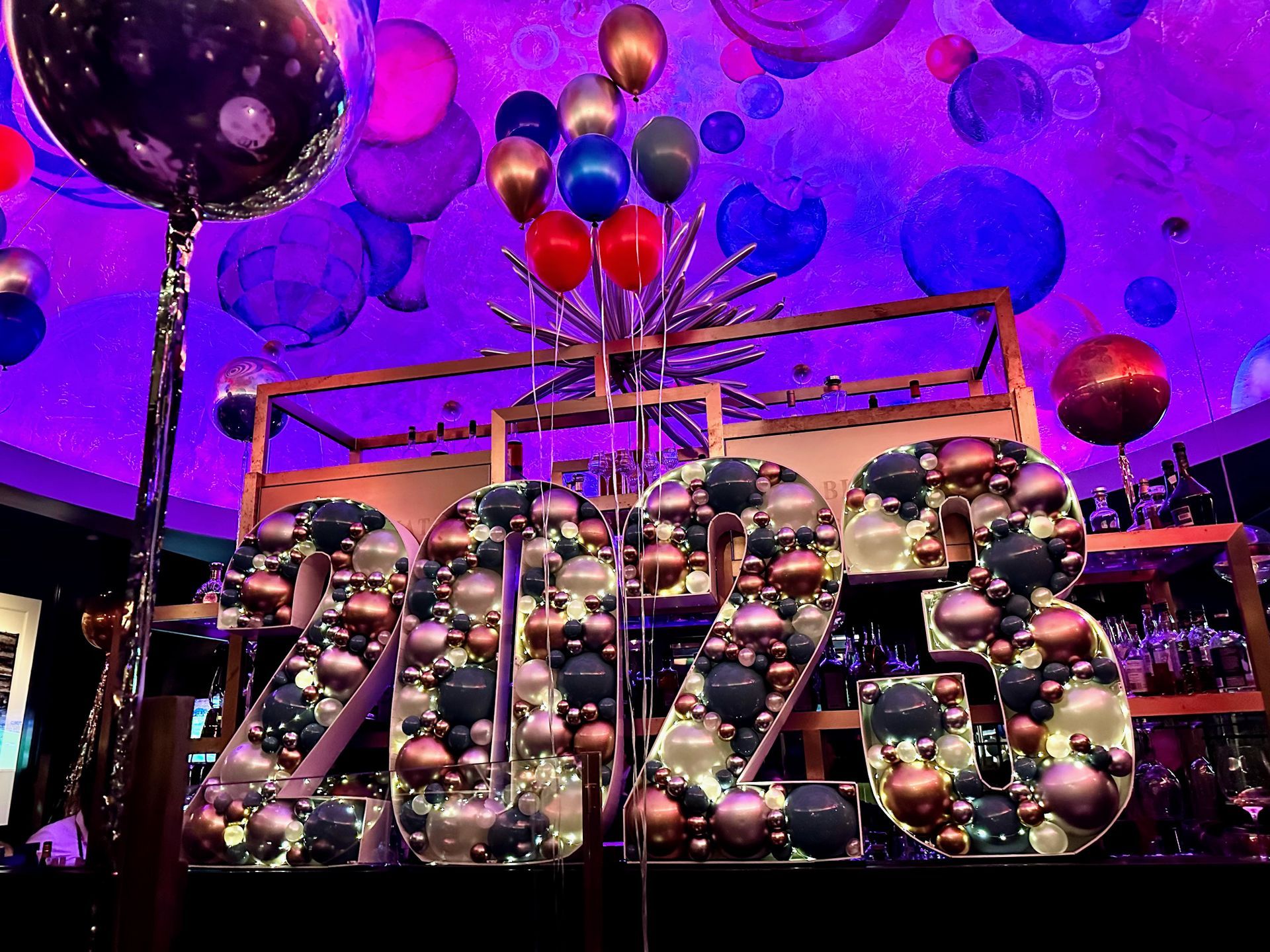 A large sign that says ' 2015 ' is surrounded by balloons and decorations.