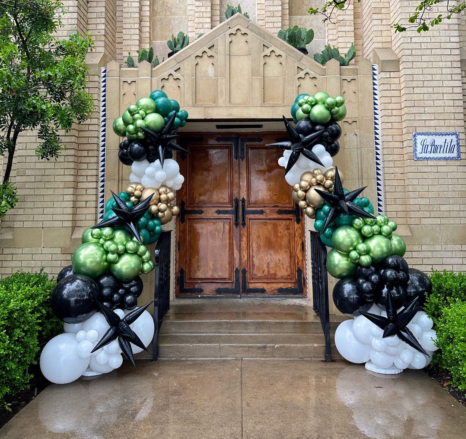 Balloon garland in green tones framing doorway entrance for event decor in Fort Worth TX