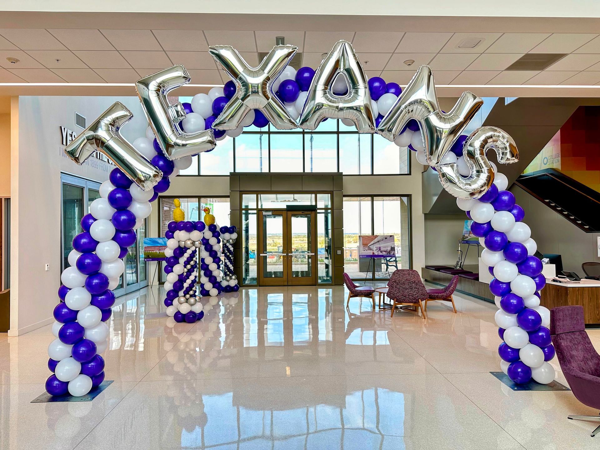 A purple and white balloon arch with the word texas on it