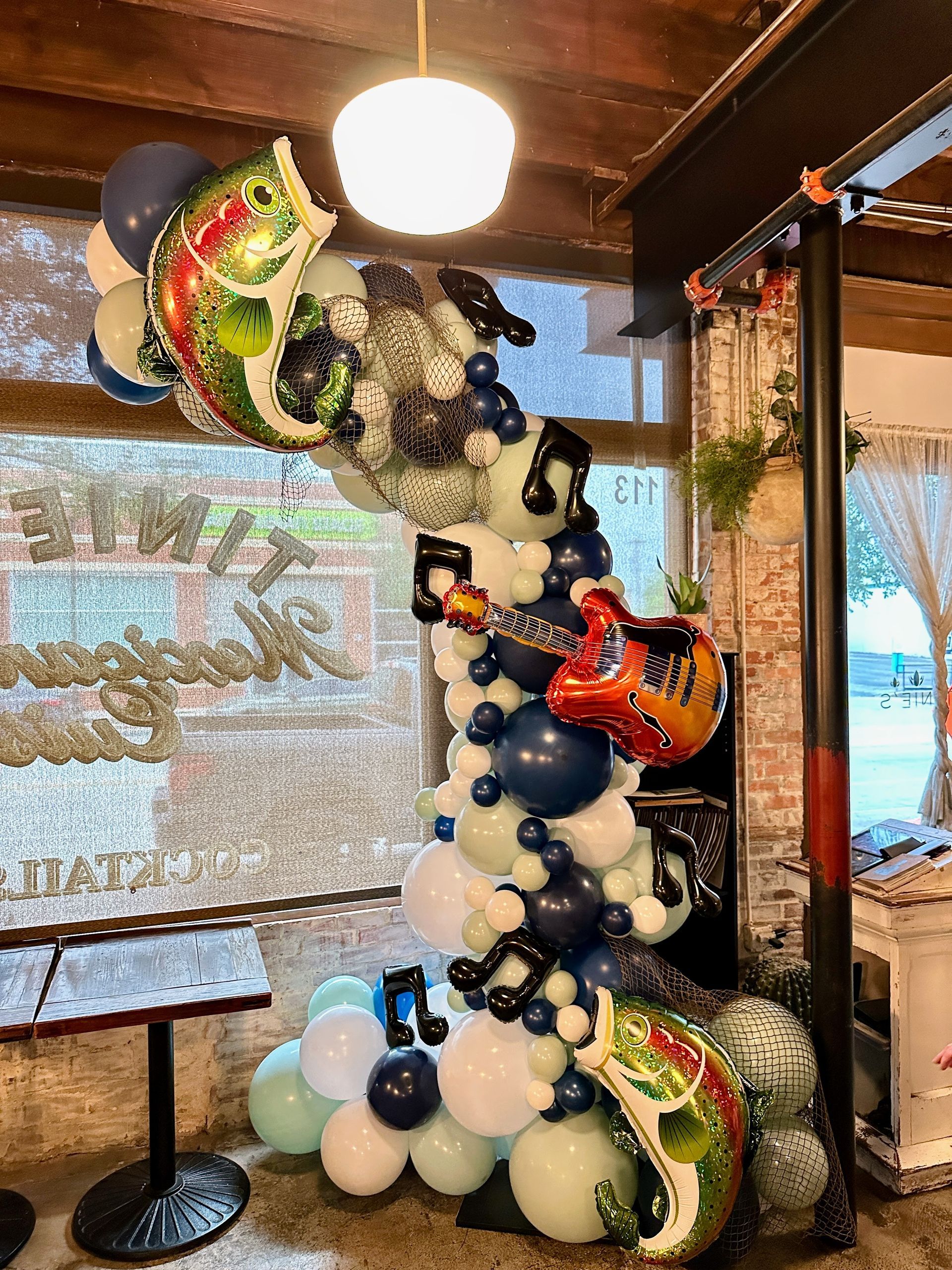 Themed balloon garland installation featuring neutral balloons and decorative accents for an indoor event