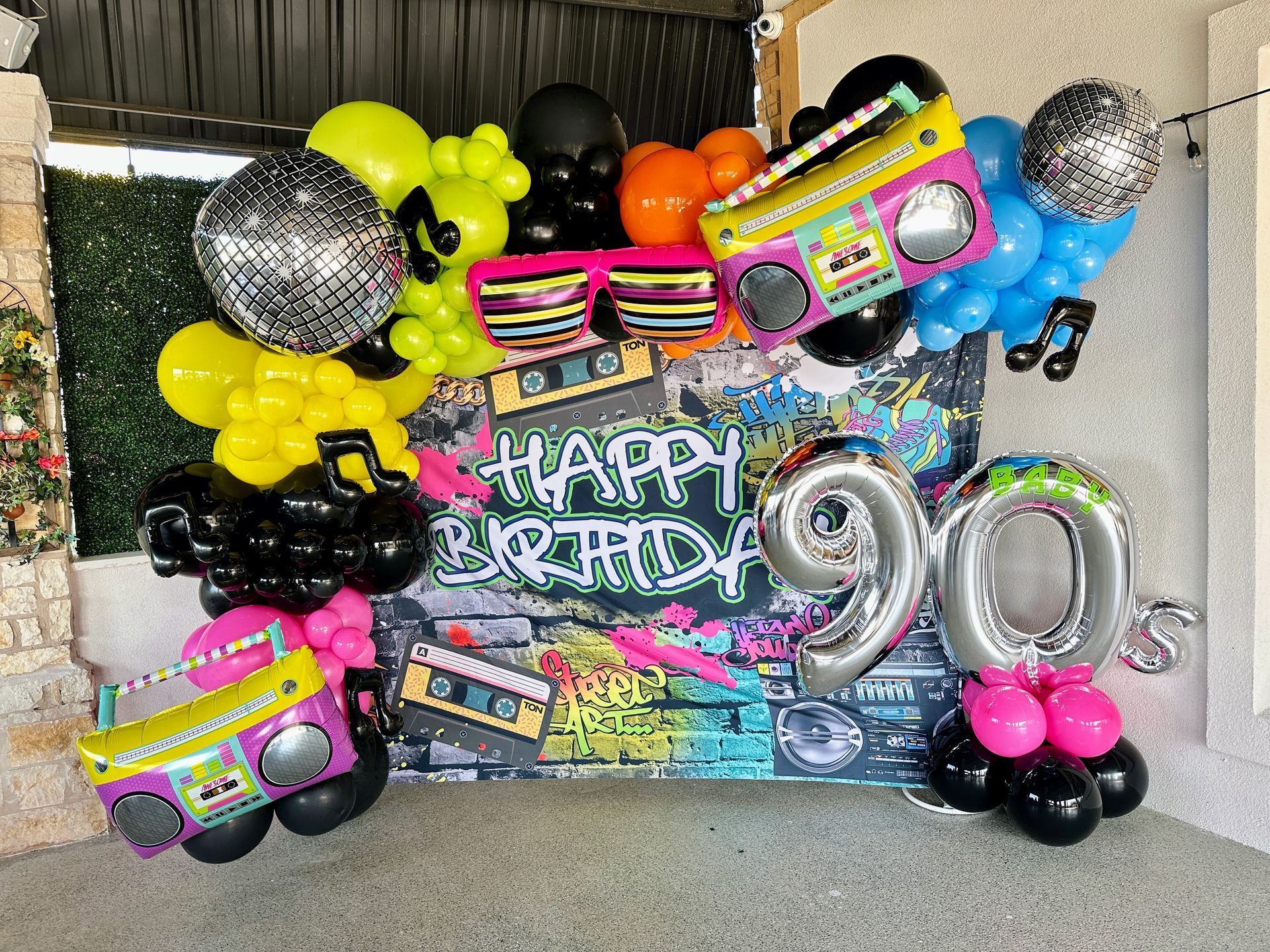 90s themed balloon garland featuring neon colors, retro props, and number balloons for a themed party
